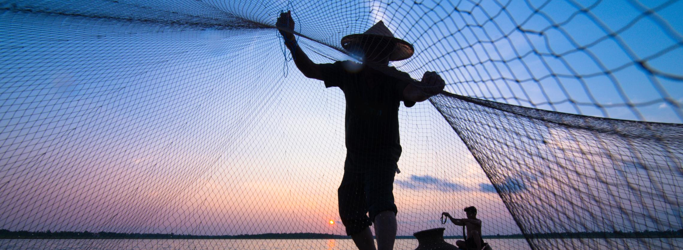 Fischer, der bei Sonnenuntergang sein Netz auswirft