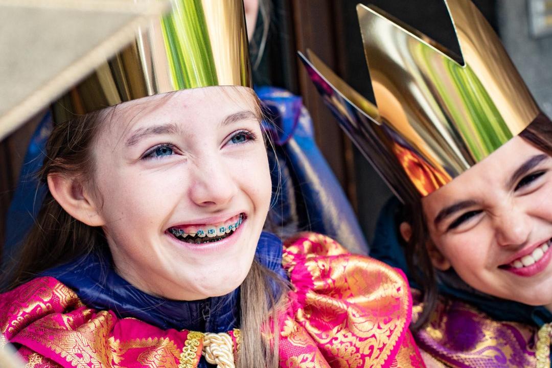 2 lachende Sternsingerinnen, darüber steht: Singe. Segne. Sammle.