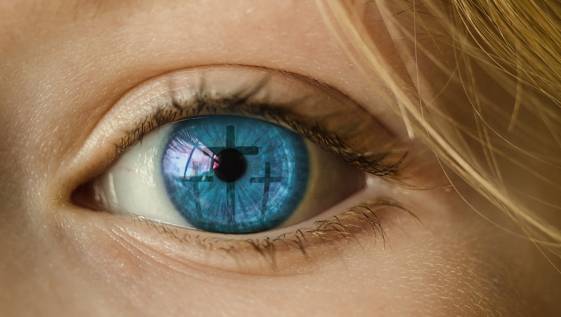 Blaues Auge, in dem sich ein Kreuz spiegelt