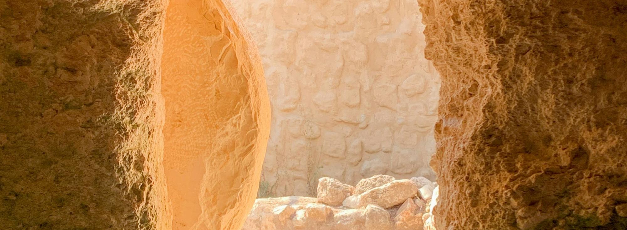 Blick aus einer Gruft durch den Eingang nach draußen. Vor dem Eingang leht ein an Seite gerollter Stein.