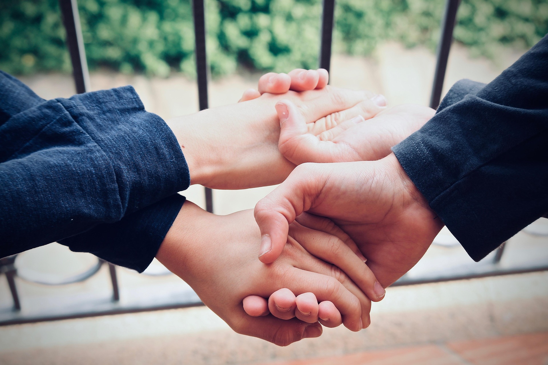Zwei Jungen, die sich mit verkreuzten Armen beide Hände reichen